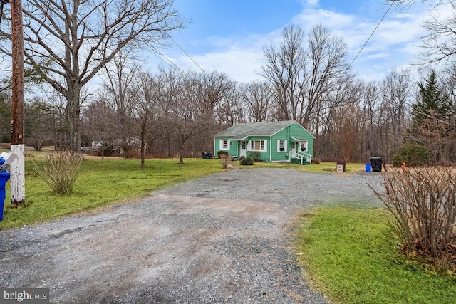 view of front of house with gravel driveway and a front lawn