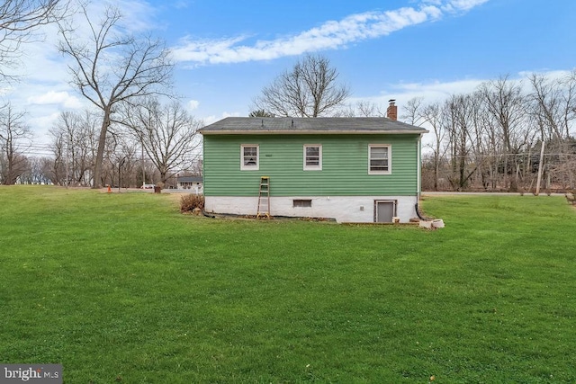 rear view of house with a chimney and a lawn