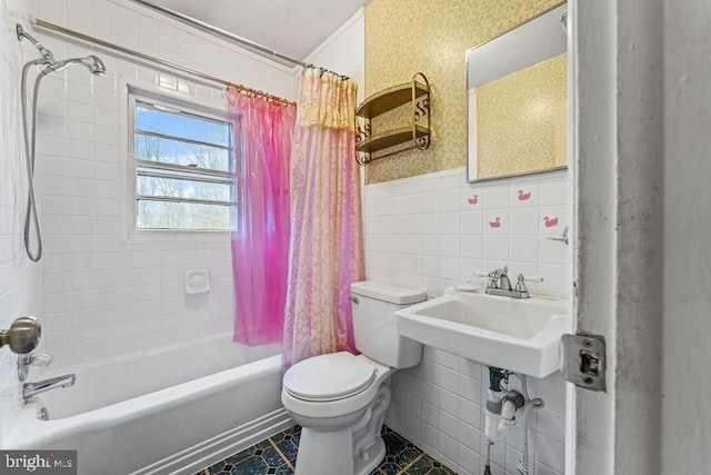 full bath with a wainscoted wall, tile walls, shower / bathtub combination with curtain, toilet, and a sink