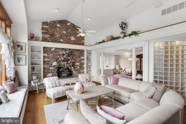 living room with light wood finished floors, lofted ceiling, visible vents, a ceiling fan, and ornate columns