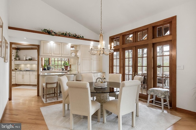 dining area featuring a chandelier, french doors, light wood-style flooring, and baseboards