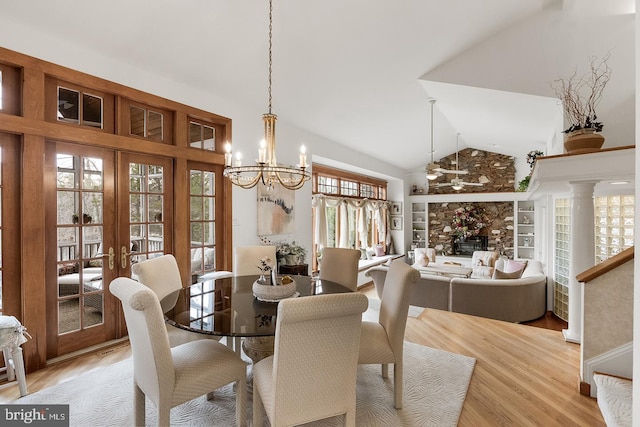 dining space with built in features, french doors, high vaulted ceiling, a chandelier, and light wood-type flooring