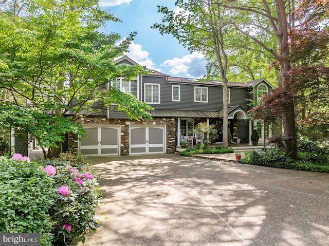 view of front facade with a garage, concrete driveway, and stone siding