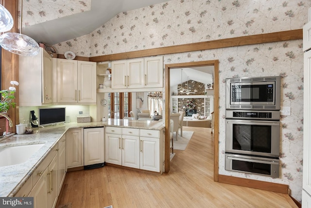 kitchen featuring lofted ceiling, wallpapered walls, and stainless steel appliances