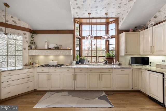 kitchen featuring vaulted ceiling, light wood-type flooring, pendant lighting, and a sink