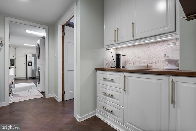 bar with tasteful backsplash, stainless steel refrigerator with ice dispenser, and baseboards