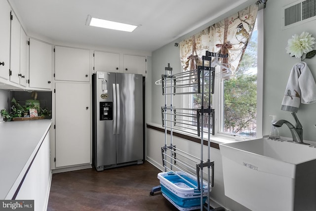 kitchen with light countertops, stainless steel fridge, visible vents, and white cabinetry