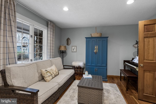 living room featuring a textured ceiling, baseboards, dark wood-type flooring, and recessed lighting