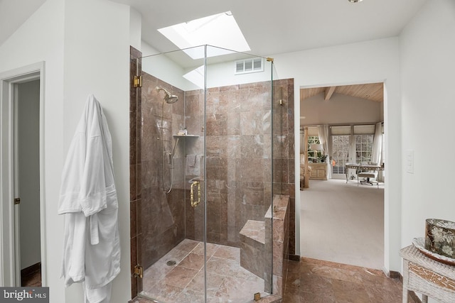 bathroom featuring vaulted ceiling with skylight, a shower stall, and visible vents