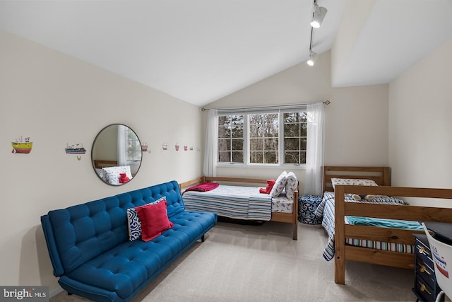 carpeted bedroom featuring lofted ceiling and rail lighting