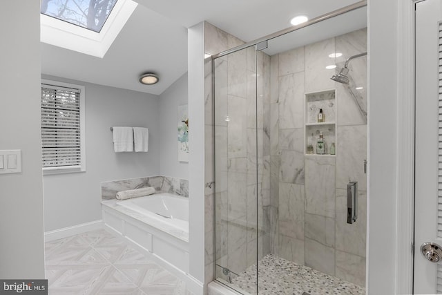 bathroom featuring vaulted ceiling with skylight, a garden tub, a shower stall, and baseboards