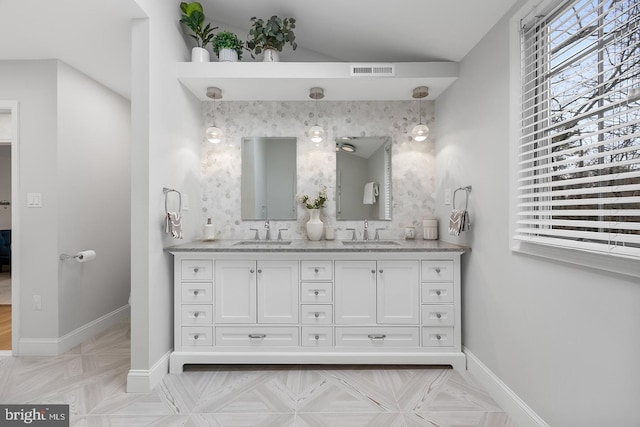 bathroom with visible vents, a sink, baseboards, and double vanity