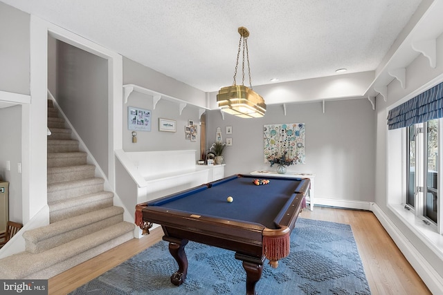 rec room featuring light wood-style floors, pool table, and a textured ceiling