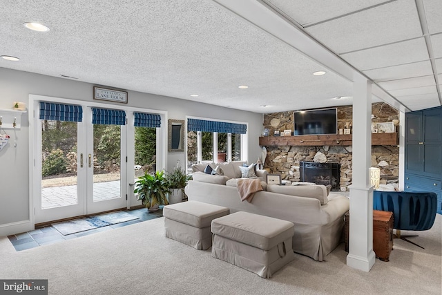 living area with french doors, a fireplace, recessed lighting, light colored carpet, and a textured ceiling