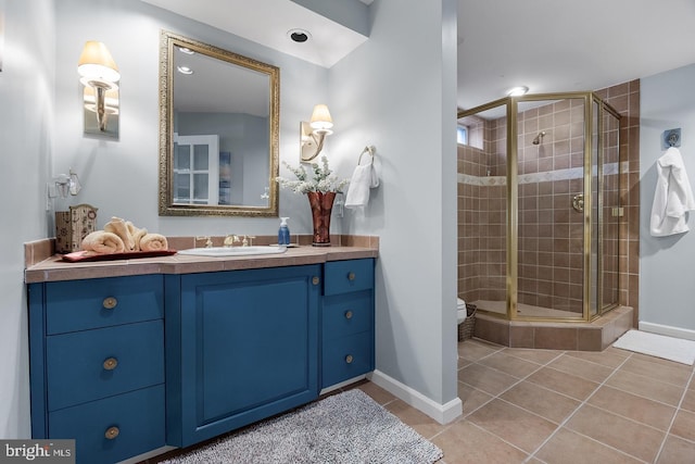 bathroom featuring a stall shower, baseboards, toilet, tile patterned flooring, and vanity