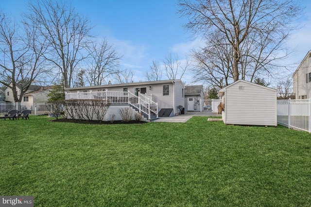 rear view of property with an outbuilding, a storage unit, a lawn, a fenced backyard, and a wooden deck