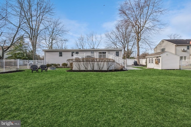 back of property with an outbuilding, a lawn, a fenced backyard, and a wooden deck