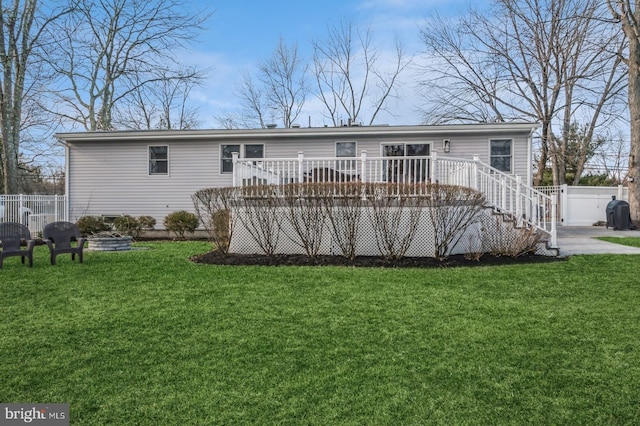 rear view of property with a lawn, fence, and a wooden deck