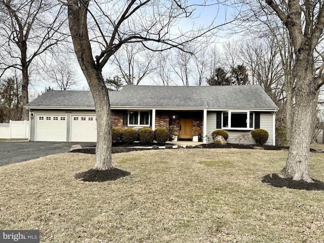 ranch-style home featuring roof with shingles, fence, a garage, driveway, and a front lawn