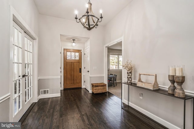 foyer entrance featuring a chandelier, dark wood-style flooring, visible vents, baseboards, and french doors