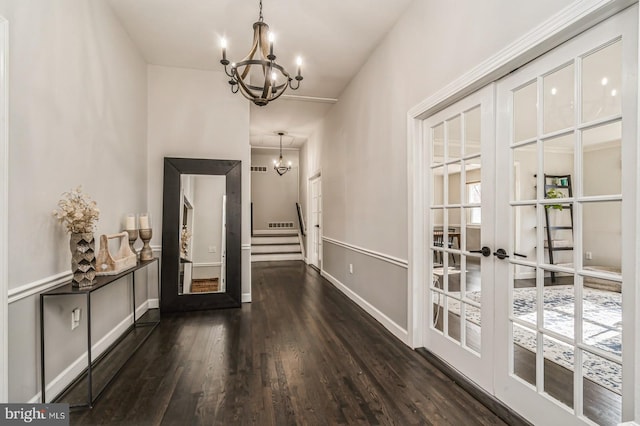 entryway featuring dark wood-style floors, french doors, a chandelier, baseboards, and stairs