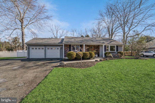 ranch-style home with an attached garage, fence, aphalt driveway, and a front yard