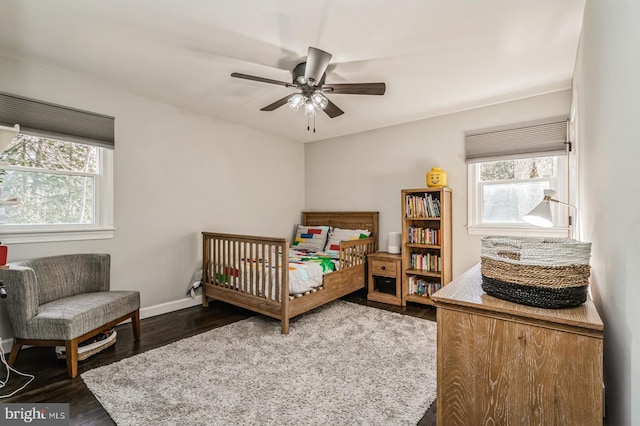 bedroom with dark wood-style flooring, multiple windows, and baseboards