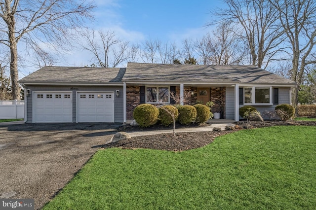 single story home featuring brick siding, fence, a garage, driveway, and a front lawn