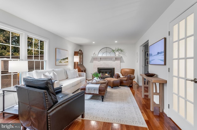 living area with a brick fireplace, wood-type flooring, and recessed lighting