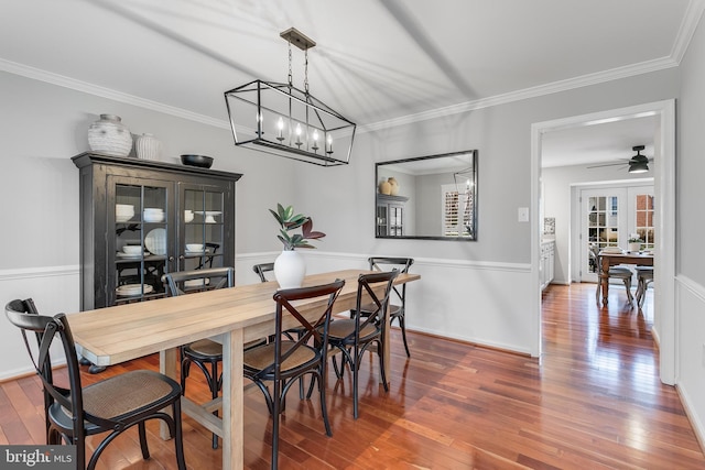 dining area featuring french doors, wood-type flooring, ornamental molding, ceiling fan, and baseboards