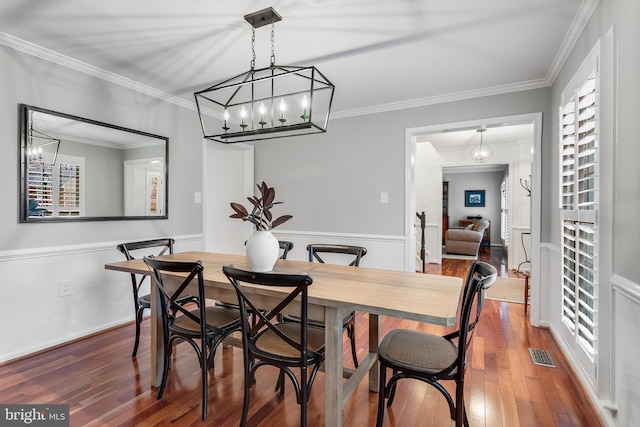 dining space with ornamental molding, hardwood / wood-style floors, and visible vents