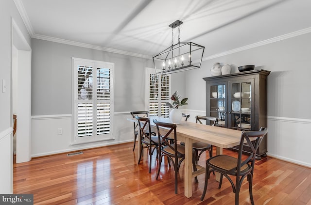 dining room with baseboards, visible vents, crown molding, and hardwood / wood-style floors