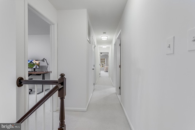 corridor with baseboards, light colored carpet, visible vents, and an upstairs landing