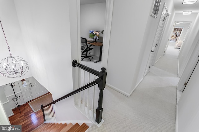 stairs with baseboards, visible vents, wood finished floors, carpet floors, and a notable chandelier