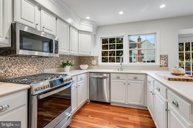 kitchen featuring stainless steel appliances, backsplash, a sink, and white cabinets