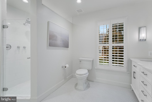 bathroom featuring toilet, baseboards, a tile shower, and a wealth of natural light