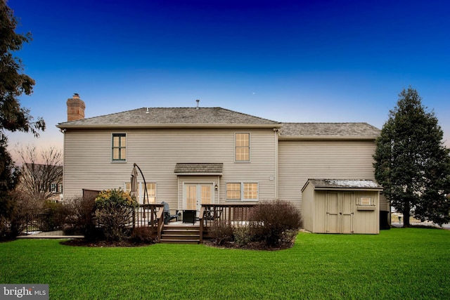 rear view of property featuring a chimney, an outbuilding, a yard, a storage unit, and french doors