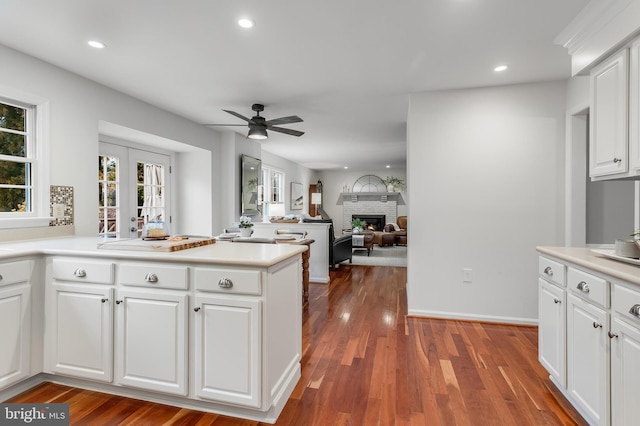 kitchen with white cabinets, dark wood finished floors, light countertops, a fireplace, and recessed lighting