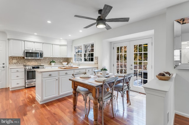 kitchen featuring french doors, tasteful backsplash, light countertops, light wood-style flooring, and appliances with stainless steel finishes