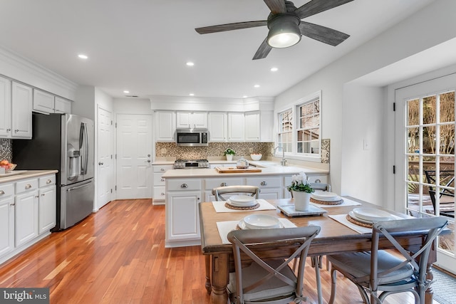 kitchen with light wood-type flooring, white cabinetry, stainless steel appliances, and light countertops