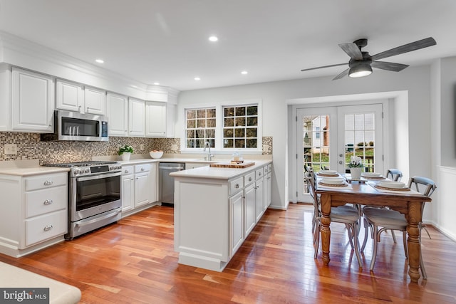 kitchen with stainless steel appliances, light wood-type flooring, backsplash, and a healthy amount of sunlight