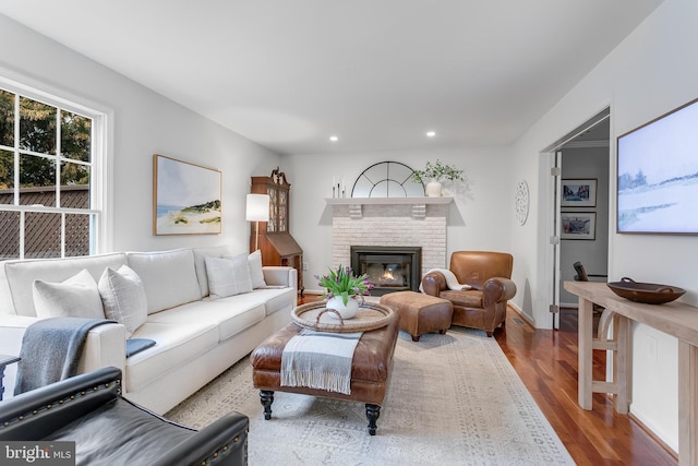 living room featuring a brick fireplace, wood finished floors, and recessed lighting