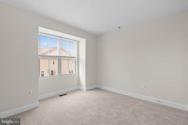 empty room featuring light colored carpet, visible vents, and baseboards