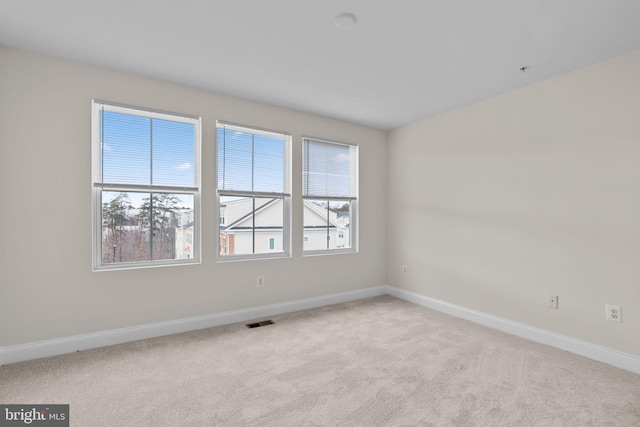 spare room with baseboards, visible vents, and light colored carpet