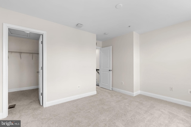 unfurnished bedroom with visible vents, baseboards, light colored carpet, a spacious closet, and a closet