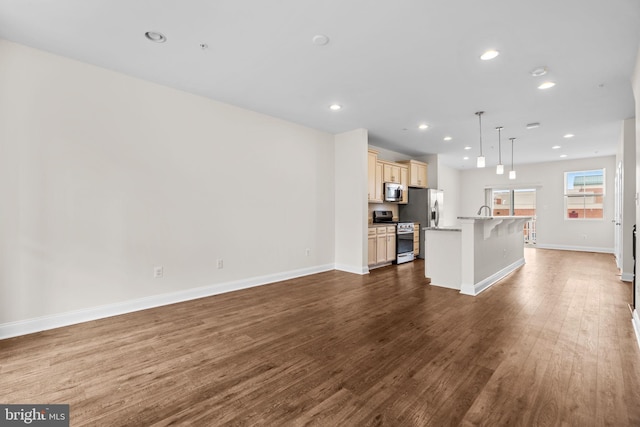 unfurnished living room with dark wood-type flooring, recessed lighting, a sink, and baseboards