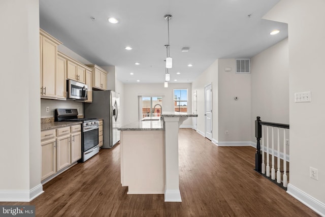 kitchen featuring light stone counters, stainless steel appliances, a breakfast bar, visible vents, and an island with sink