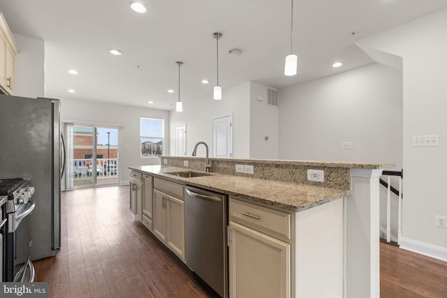 kitchen featuring hanging light fixtures, cream cabinets, a kitchen island with sink, stainless steel appliances, and a sink