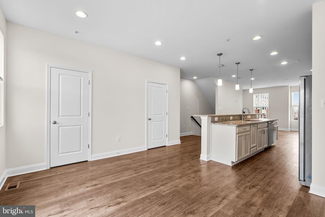 kitchen with visible vents, hanging light fixtures, appliances with stainless steel finishes, dark wood-style floors, and a center island with sink