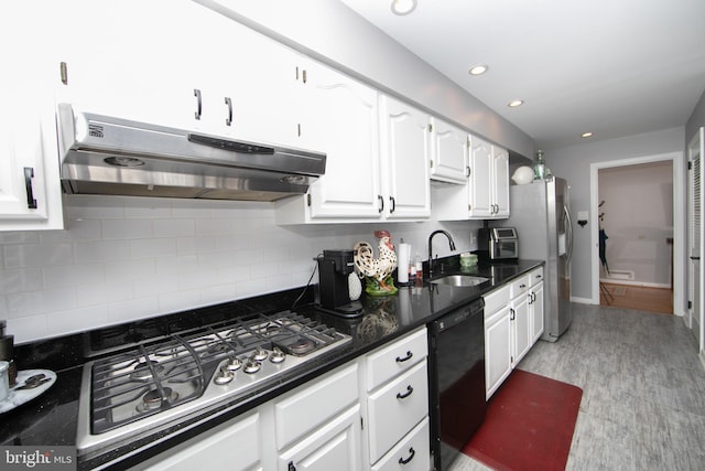 kitchen featuring white cabinets, appliances with stainless steel finishes, a sink, under cabinet range hood, and backsplash